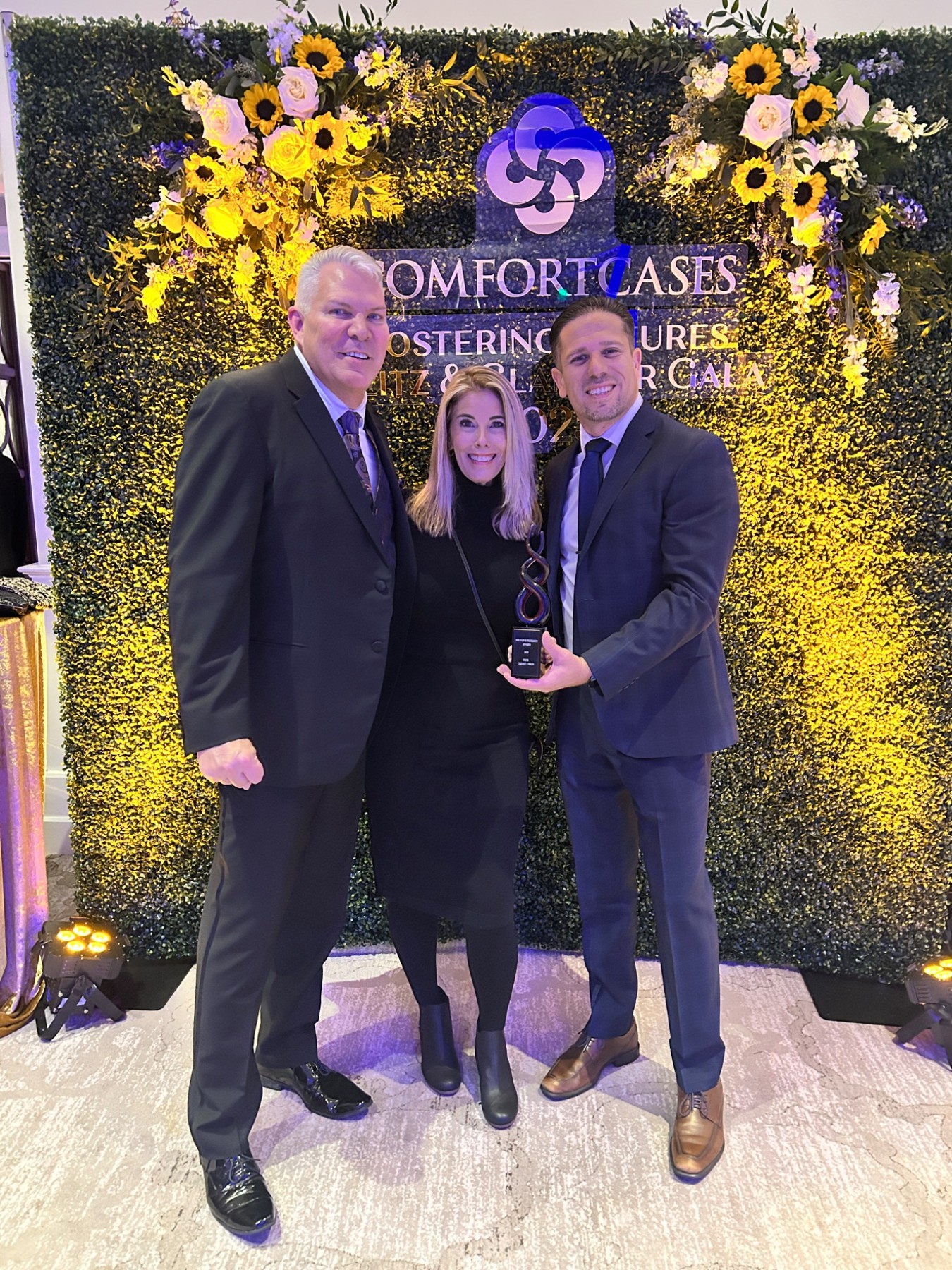 Lenny with fellow attendees holding an award at a Comfort Cases gala